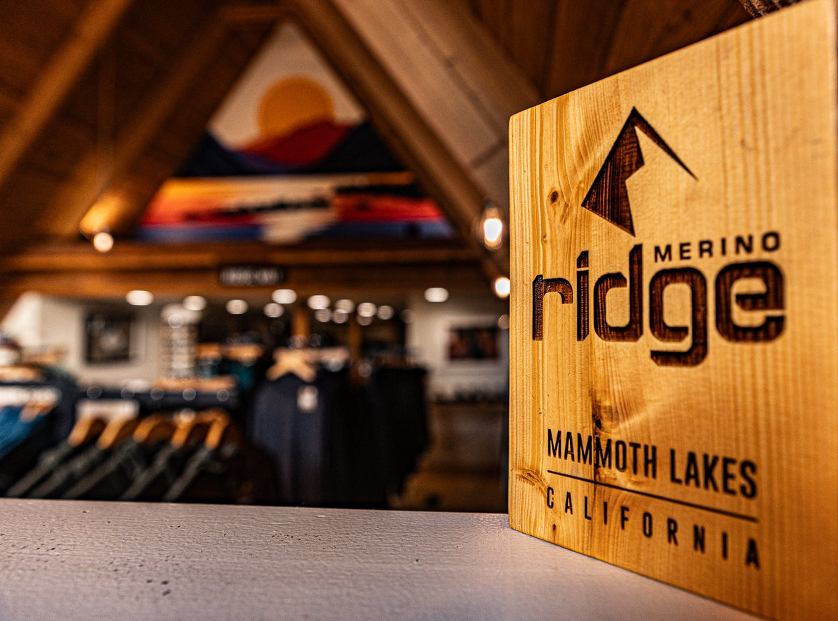 Wooden sign with 'Merino Ridge' branding in a blurred indoor setting